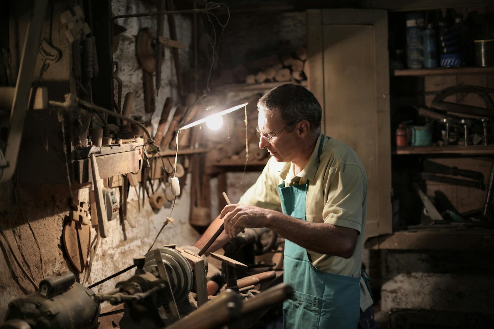 A focused craftsman honing his skills in a dimly lit workshop with tools.