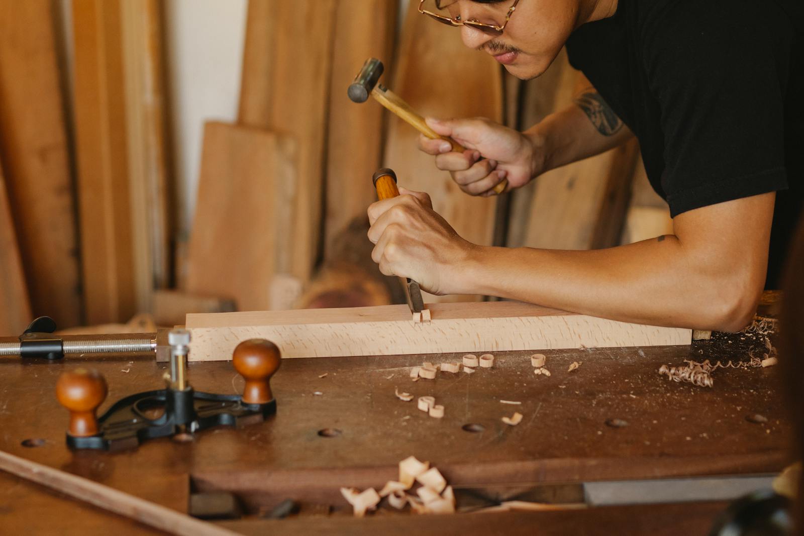A focused craftsman intricately chiseling wood at a workbench, showcasing traditional woodworking skills.
